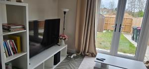 a living room with a flat screen tv and a window at Private room in a 2-bedroom house in Dinnington