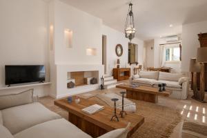 a living room with white furniture and a tv at Horizon Beach House by Andros Villas Collection in Andros