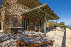 a brick house with an outdoor patio with a pergola at Horizon Beach House by Andros Villas Collection in Andros