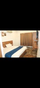a bedroom with a bed with a blue blanket at Hotel Meghdoot in Pachmarhī