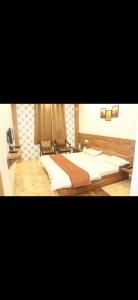 a bedroom with a large bed with white sheets at Hotel Meghdoot in Pachmarhī