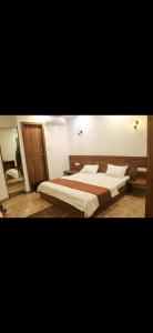 a bedroom with two beds with white sheets and wood accents at Hotel Meghdoot in Pachmarhī +11 photos