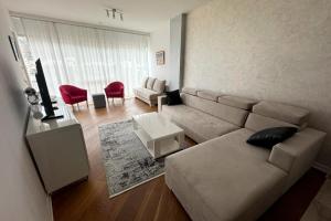 a living room with a sectional couch and red chairs at Tre Canne Vista in Budva