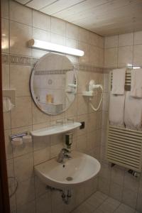 a white bathroom with a sink and a mirror at Hotel Tannhof in Feldberg