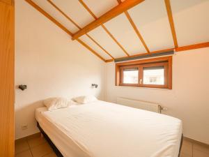 ein weißes Bett in einem Zimmer mit Fenster in der Unterkunft Zeepark Haerendycke in Wenduine