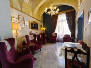 a waiting room with chairs and a table and a chandelier at Julina Boutique Living in Mosta
