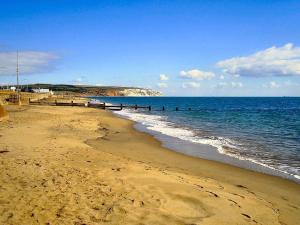 a beach with a group of people in the water at Seaside Serenity at Ocean Days in Brading +23 photos