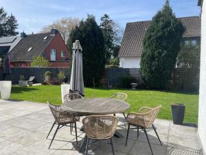 a patio with a table and chairs and an umbrella at Ferienhaus Heimatgefühl in Würselen