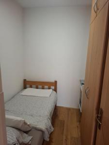 a small bedroom with a bed and a wooden floor at Apartman Mirjana in Mlini