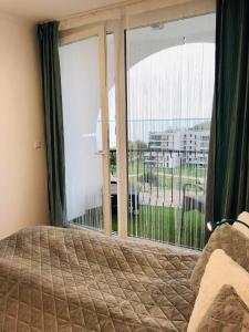 a bedroom with a bed and a large window at Türkiz Apartman in Siófok