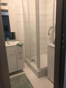 a white bathroom with a shower and a sink at Türkiz Apartman in Siófok
