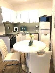 a small kitchen with a white table and chairs at Türkiz Apartman in Siófok