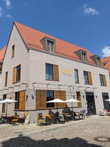 ein großes Gebäude mit Tischen, Stühlen und Sonnenschirmen in der Unterkunft Hotel-Weingut Bernard in Sulzfeld am Main
