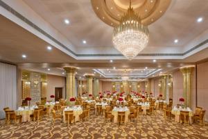 a banquet hall with tables and chairs and a chandelier at Olivia International in Alleppey +33 photos