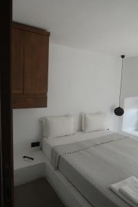 a white bedroom with a bed and a wooden cabinet at Yalikavak Manzarali Villa in Bodrum City