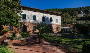 a large stone building with chairs in a yard at Borgo degli Aranci in San Giuliano Terme