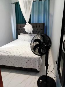 a bedroom with a bed with a fan next to it at Peaceful Home Self-catering Solar Backed Apartment in Lusaka