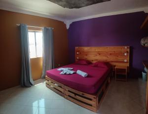 a bedroom with a large bed with purple sheets at casa alcindo in Portela