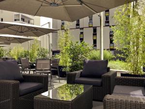a patio with chairs and tables and an umbrella at Mercure Clermont Ferrand centre Jaude in Clermont-Ferrand
