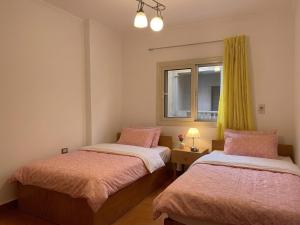 two beds in a small room with a window at Maison de Lama - Expat friendly, AirCon, Garden access in Cairo +6 photos