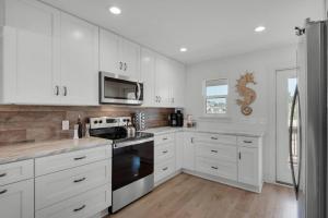 a kitchen with white cabinets and a stove top oven at Beachfront 6BR Retreat w Gulf Views Sleeps 16 in Port Saint Joe +34 photos
