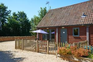 a small house with a wooden fence and an umbrella at Barn Cottages at Lacock in Lacock