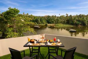 a table with food on a balcony with a view of a river at Olivia International in Alleppey