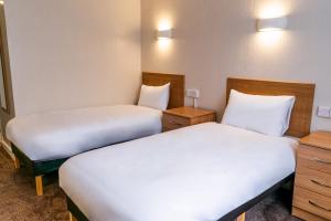 two beds in a hotel room with white sheets at Coventry Hill Hotel in Coventry