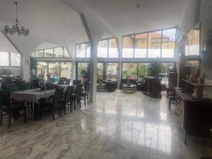 ein Esszimmer mit Tischen, Stühlen und Fenstern in der Unterkunft Hotel Ostrov in Călimăneşti