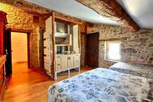 a bedroom with a bed and a stone wall at Le Triol in Les Fournials +30 photos