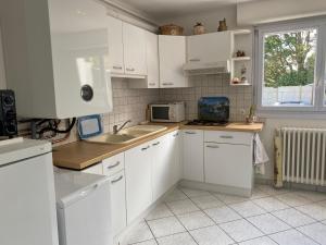 a kitchen with white cabinets and a sink and a microwave at Paisible in La Celle-sous-Gouzon