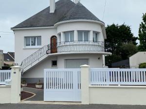 a white house with a white fence and a balcony at Paisible in La Celle-sous-Gouzon