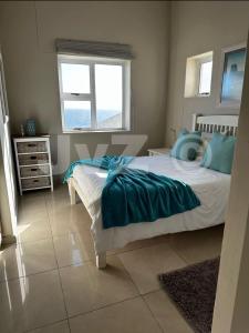 a bedroom with a bed with blue sheets and a window at Dolphin View 32 in Langstrand +5 photos