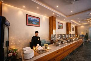 a man is standing behind a counter with food at Manali Valley Resort in Manāli