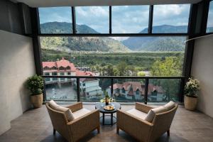 a room with a large window with chairs and a table at Manali Valley Resort in Manāli