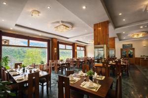 a restaurant with wooden tables and chairs and windows at Manali Valley Resort in Manāli