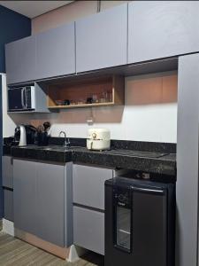 a kitchen with white cabinets and a black counter top at D Castro Residencial in Montes Claros