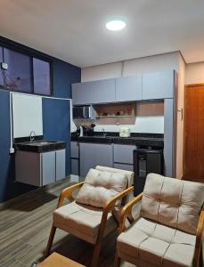 a living room with two chairs and a kitchen at D Castro Residencial in Montes Claros