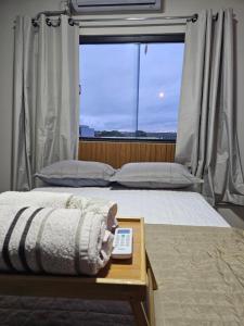 a bedroom with a bed with a window and a table at D Castro Residencial in Montes Claros