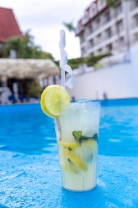 a drink with a lemon slice on a table next to a pool at Hotel Croma Sosua Beach in Sosúa