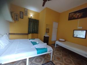 a bedroom with a white bed and a tv at NEW BEACH HOTEL Anjuna in Anjuna