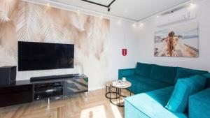 a living room with a green couch and a flat screen tv at Apartament 19A - Villa Neptun in Gdańsk