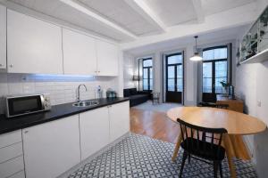 a kitchen with white cabinets and a wooden table at Oporto City View - Trindade in Porto