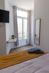a bedroom with a large bed with a large window at Les suites du pont Joffre in Perpignan
