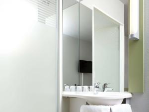 a bathroom with a sink and a mirror at ibis budget Pontarlier in Pontarlier +28 photos