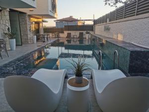 a patio with white chairs and a swimming pool at Olea Alacati in Çeşme