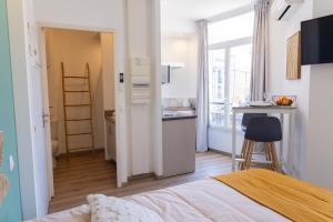 a bedroom with a bed and a kitchen with a desk at Les suites du pont Joffre in Perpignan
