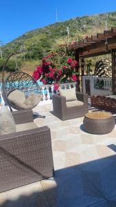 a patio with wicker chairs and tables and flowers at Pousada Thetis in Arraial do Cabo