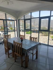 a dining room with a table and chairs and windows at casa alcindo in Portela