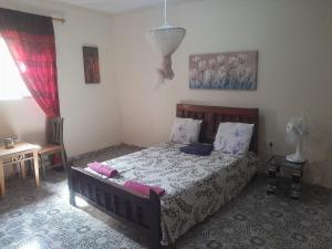 a bedroom with a bed and a table with a fan at Sunshine Guesthouse Bafuloto in Bafuloto